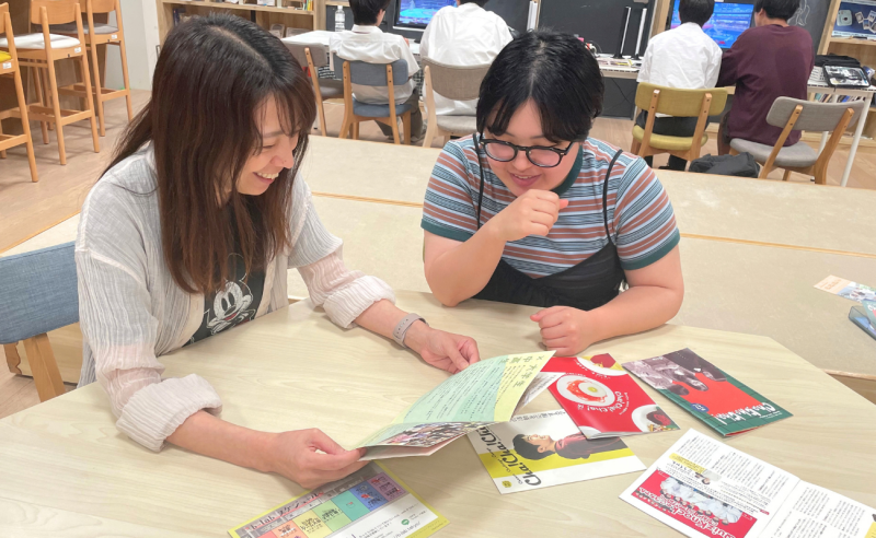 佐渡と一緒に当時の制作物（フリーペーパー）を見ながら振り返る様子